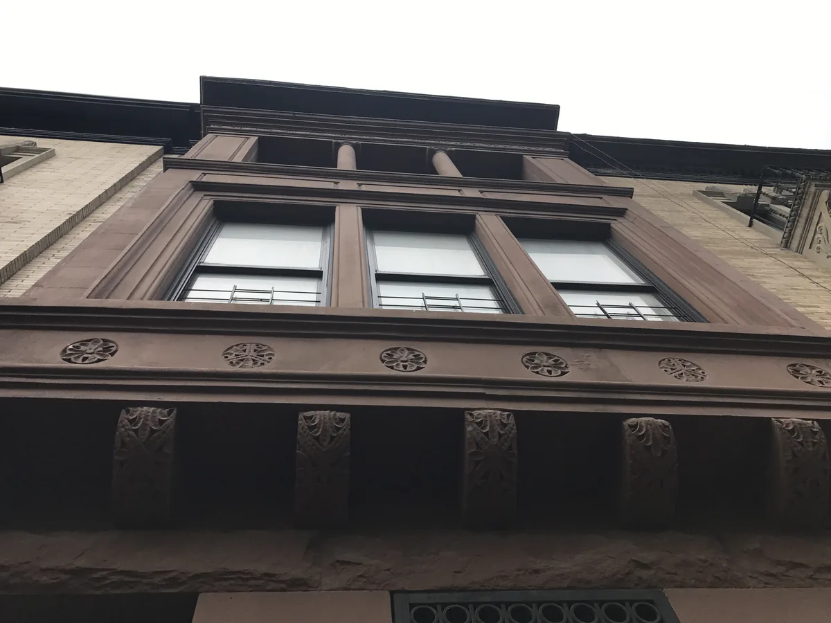 Brownstone upper facade and cornice used by roosting birds in Manhattan